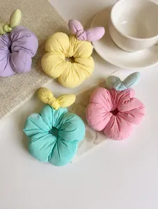 Flat lay of macaron-colored fabric flower scrunchies with bunny ears in four soft pastel tones