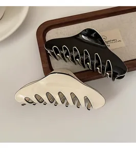 Close-up of glossy black and cream wavy hair claws on a rustic wooden tray decoration