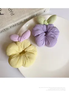 Close-up of soft floral fabric scrunchies in yellow and purple with bow details