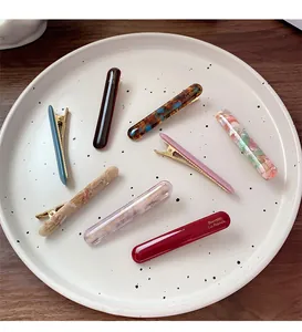 Close-up of 8 acetate hair clips set in various marble patterns and solid colors