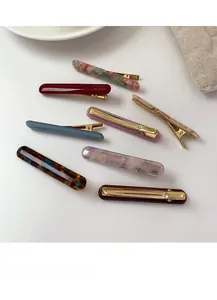 Detailed view of eight acetate hair clips with marble patterns and French lettering