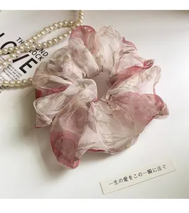 Detailed close-up of floral organza scrunchie with layered fabric and red flower patterns