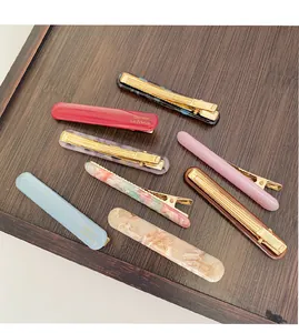 Detailed view of seven acetate hair clips with marble patterns on a wooden tray