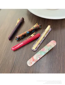 Close-up of five acetate hair clips in various colors on a dark wooden background
