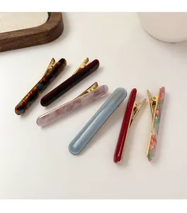 Detailed view of various acetate duckbill hair clips with elegant patterns and gold metal clips