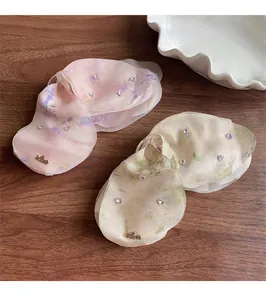 Dettaglio di fermagli per capelli in organza con strass e ciondolo in metallo Love