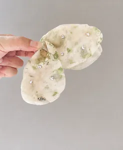 Dettaglio della pinza per capelli in chiffon verde chiaro con cristalli e ciondolo Love