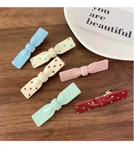 Gros plan de six barrettes à cheveux à nœuds colorés à pois sur une table en bois