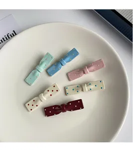 Lot de 6 pinces à cheveux à nœuds et pois colorés dans un plat en céramique blanc