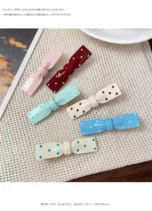 Détail de six barrettes nœuds colorées à pois sur un fond texturé chaleureux