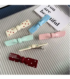 Détail de barrettes à nœuds colorés à pois dans diverses finitions pastel en résine