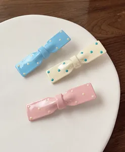 Détail de pinces à cheveux nœuds à pois en bleu pastel, crème et rose tendre