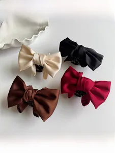 Detail showing various satin bow claw clips in black, beige, wine red, and brown colors
