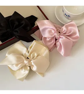 Detailaufnahme großer Satin-Haarschleifen in Schwarz, Rosa und Champagner-Gold