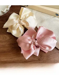 Detailansicht der rosa und cremefarbenen Satin-Haarschleifen mit seidiger Textur