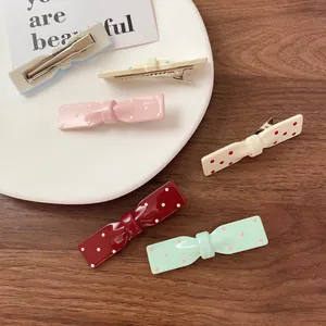 Barrettes à cheveux nœud à pois colorés présentées sur une assiette en céramique