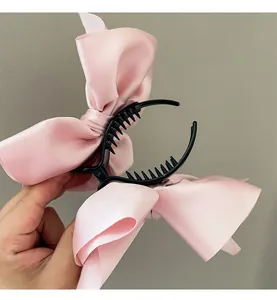 Nahaufnahme der rosa Satin-Schleifen-Haarklammer mit glattem Stoff und schwarzen Zähnen