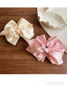 Details von übergroßen Satin-Haarspangen in Champagner und Rosa mit seidiger Textur