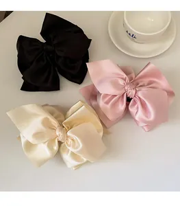 Detailansicht der übergroßen Satin-Haarschleifen in Schwarz, Rosa und Cremeweiß