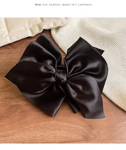 Detailaufnahme der übergroßen schwarzen Satin-Haarschleife mit seidig glänzender Textur