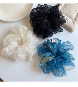 Gros plan de trois chouchous en organza bleu, noir et blanc avec motifs à pois