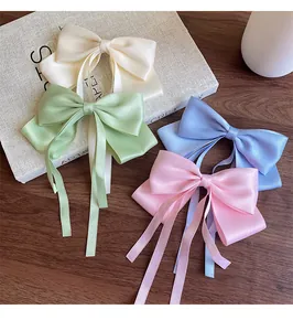 Detail of satin bow hair clips with long ribbons in soft pastel cream and pink