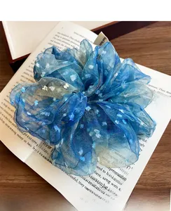Détail d'un chouchou en dentelle bleue à pois blancs posé sur un livre ouvert rustique