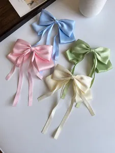 Detail of four colorful satin bow hair clips with long ribbons in pastel colors