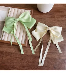 Detail of satin bow hair clips with long streamers in mint green and cream white colors