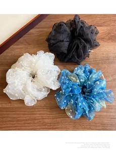 Détail de trois chouchous en tulle à pois sur une surface en bois naturel