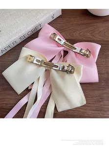 Detailed view of pink and beige satin bow hair clips with silver metal spring fasteners