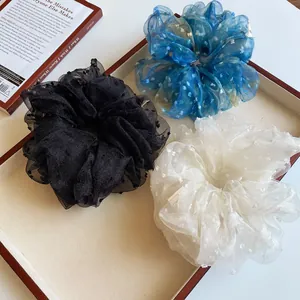 Trois chouchous élégants en dentelle à pois bleus, noirs et blancs sur plateau bois