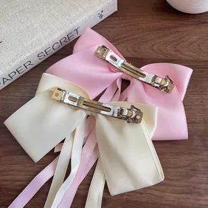 Pink and beige satin bow hair clips with silver spring metal fasteners on wood