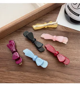 Dettaglio di fermagli per capelli a fiocco in acetato colorato in sei colori su legno