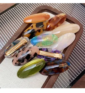 Detailed macro view of assorted acetate oval hair clips with gold metal spring clips