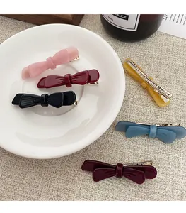 Dettaglio di fermagli per capelli a fiocco in acetato colorato su tessuto strutturato