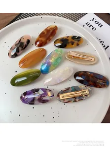 Macro view of oval acetate hair clips with tortoiseshell texture and gold metal clasp