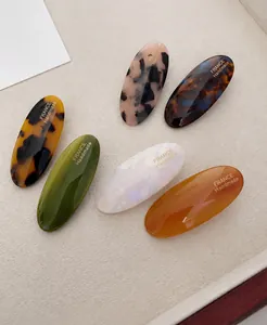 Set of 6 oval acetate hair clips in tortoiseshell and marble patterns with gold lettering