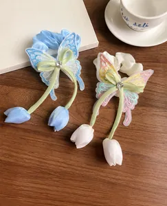 Détails de chouchous papillon avec rubans de soie et breloques tulipes sur un bureau