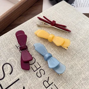 Set di quattro fermagli per capelli colorati in viola, giallo e blu su sfondo beige naturale