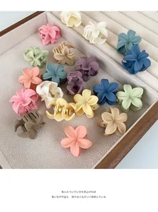 Primer plano de pinzas para el cabello con forma de flor mate en caja de terciopelo beige
