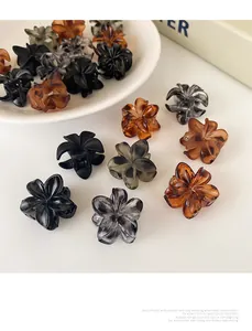 Primer plano detallado de pinzas para el cabello con flores acrílicas en bandeja blanca