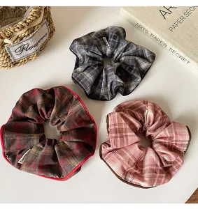 Detailed view of plaid scrunchies in red, black, and pink with contrast edge stitching