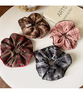 Detail view of plaid fabric scrunchies in red-brown, pink, gray, and khaki tones