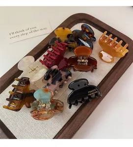 Close-up of assorted acetate hair claws with marble and tortoiseshell patterns in a tray