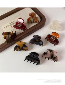 Detailed view of small acetate hair claw clips in tortoiseshell and solid colors
