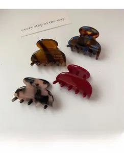Detail view of four acetate hair claws in tortoise shell and marble patterns with gold text