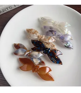 Set of 5 acetate bow hair clips in various marble patterns on a white plate