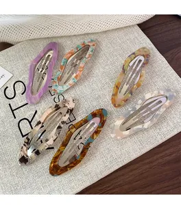Close-up of five colorful acetate cloud hair clips with marble texture and metal snaps
