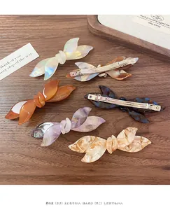 Detailed set of acetate bow hair clips in various marble and floral patterns on wood